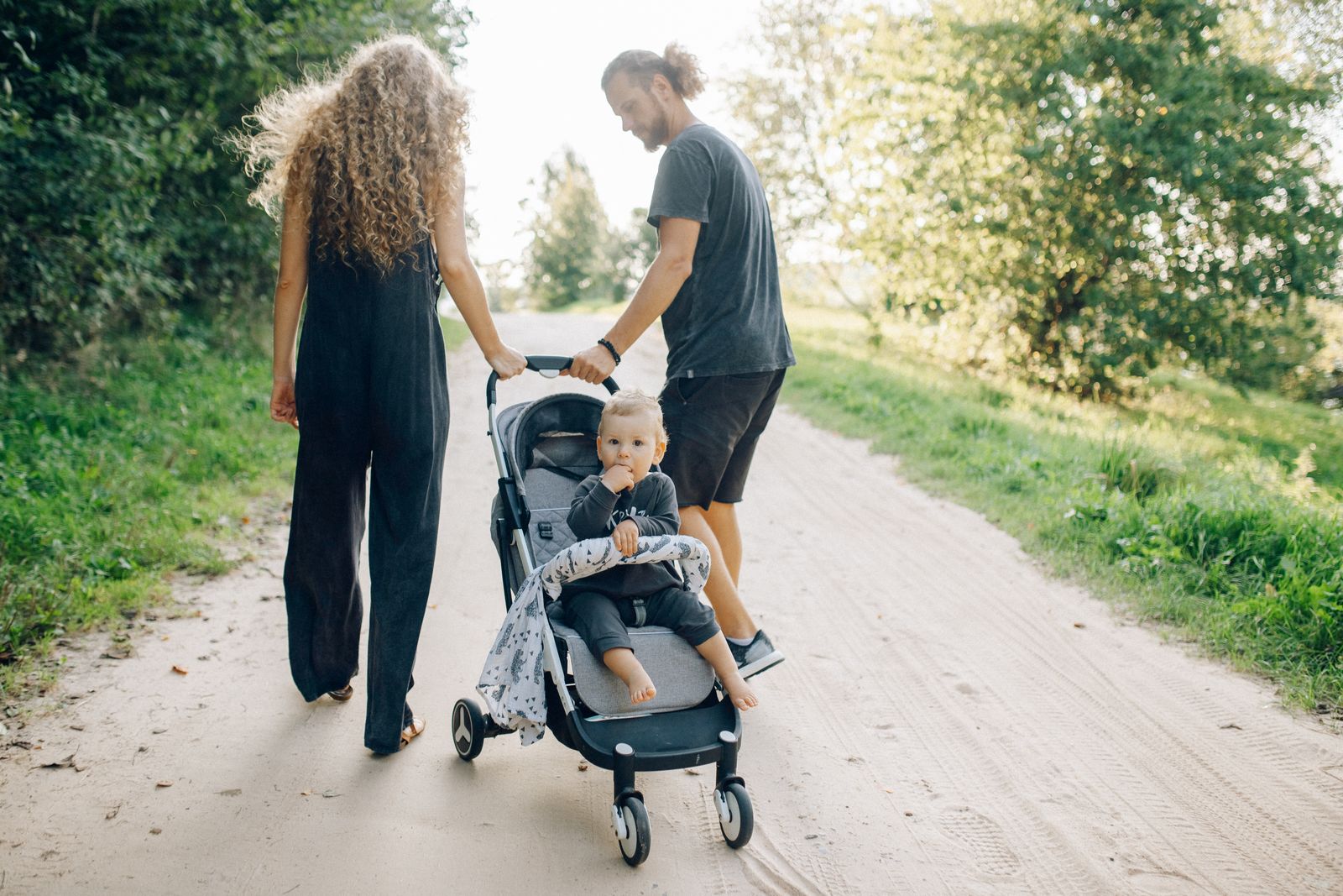 Familie på en solfylt grussti med en kompakt vogn