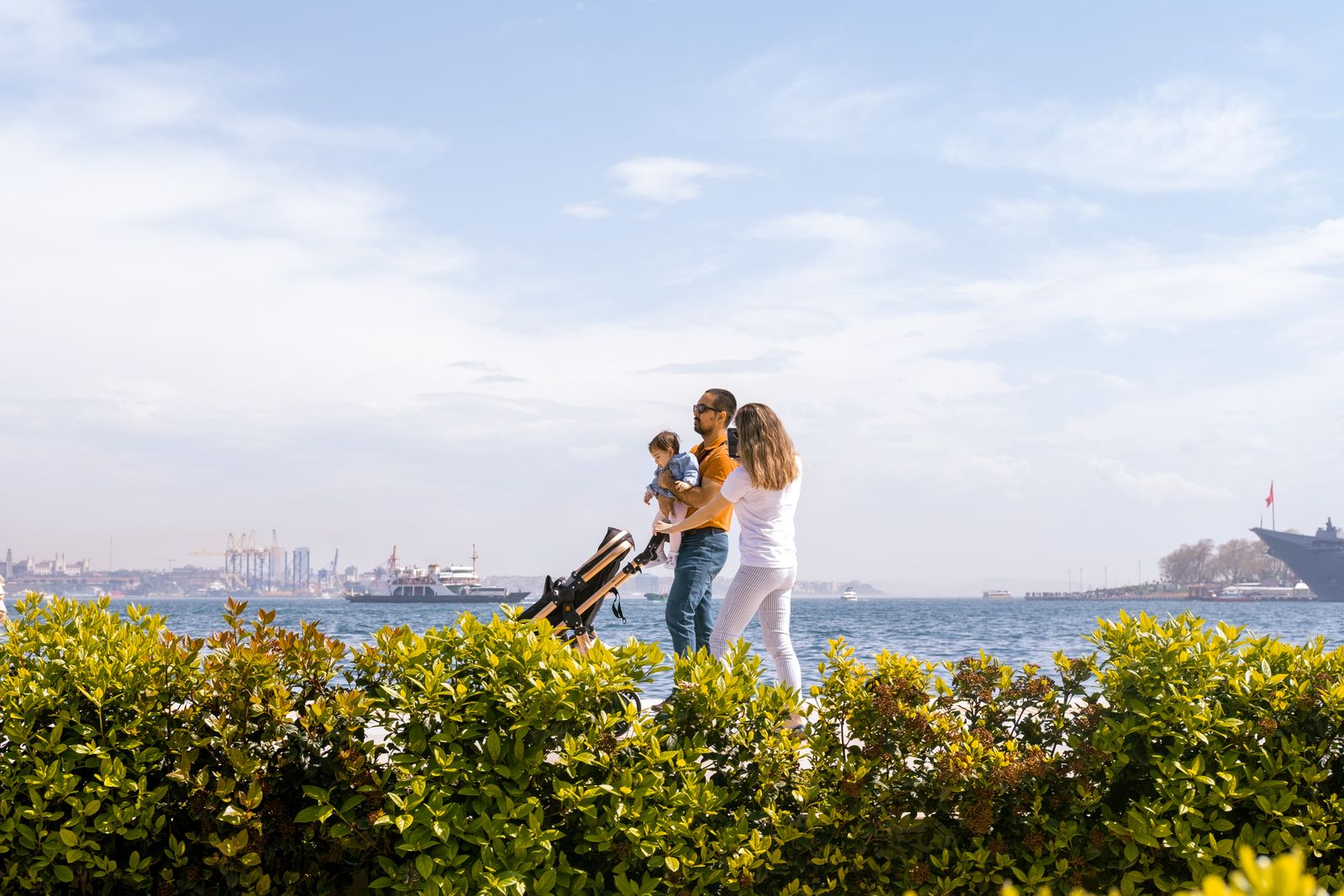 Familie med vogn på en strandpromenade under blå himmel